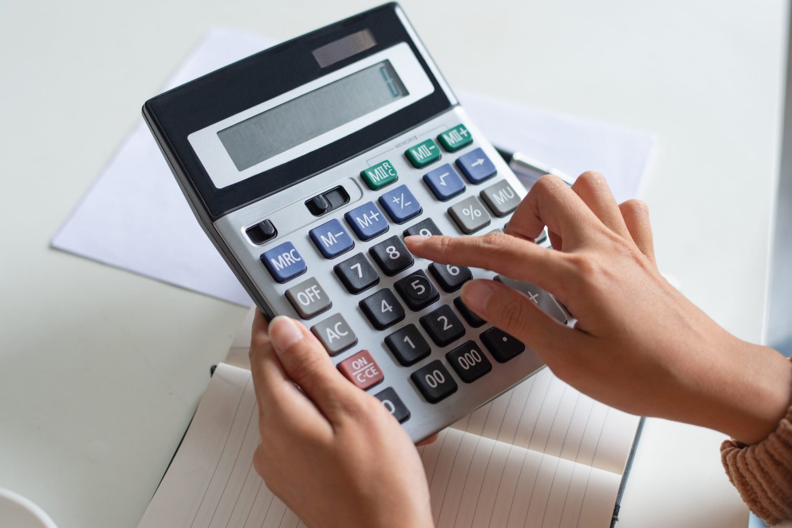 close up of accountant using calculator while examining report